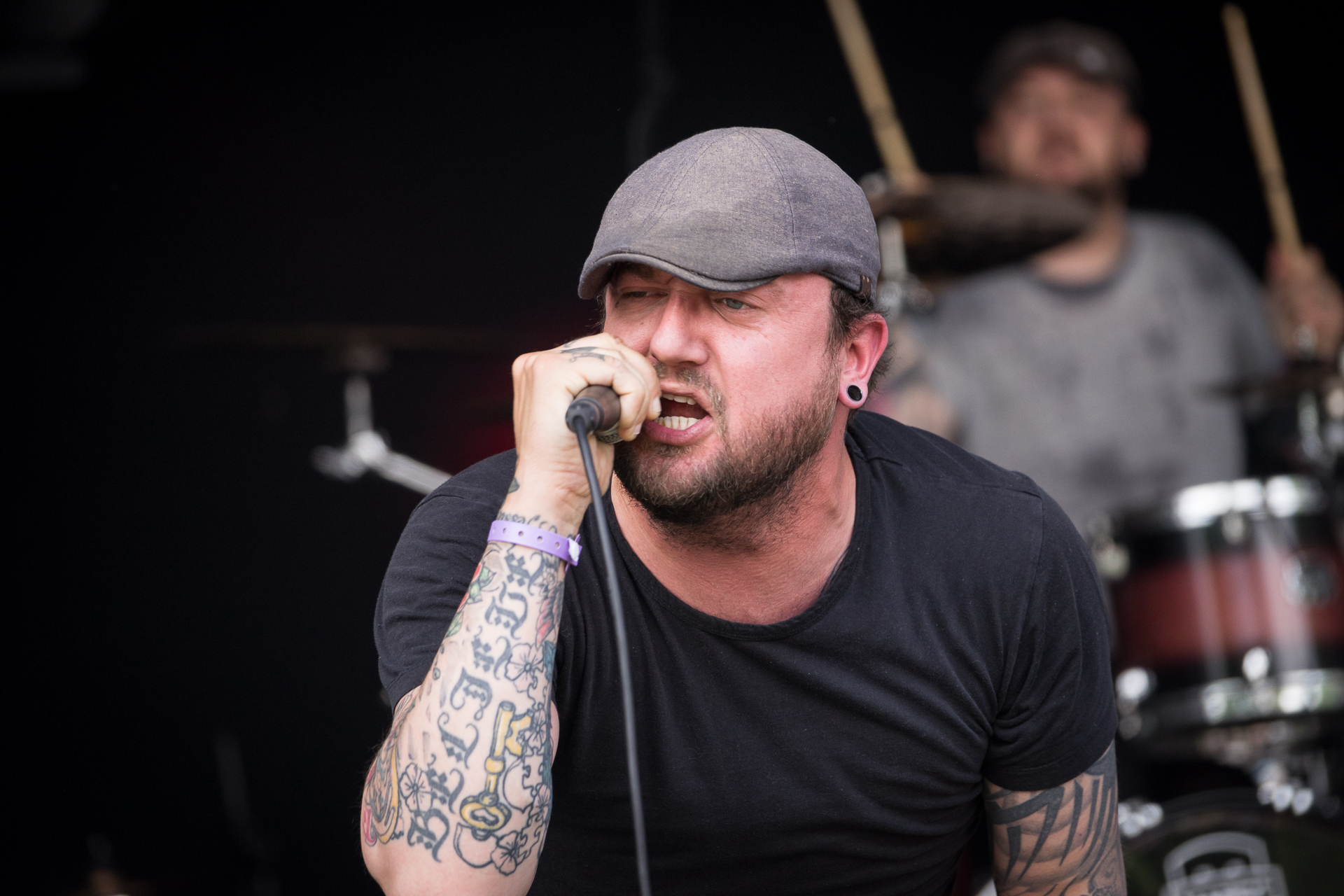 a man with a hat and piercings on is singing into a microphone