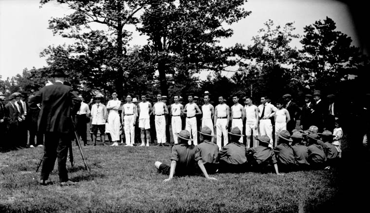 the large group of people are watching a man being held in the grass