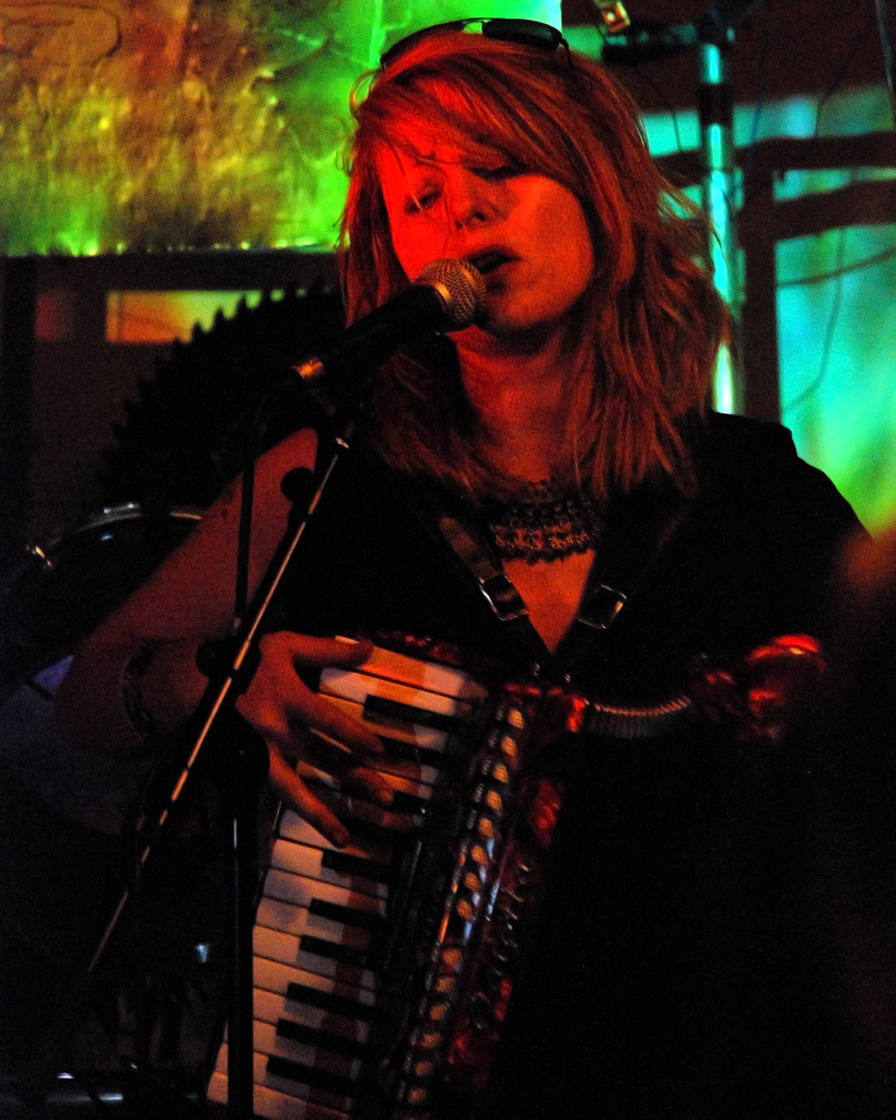 a woman with long hair playing an accordian