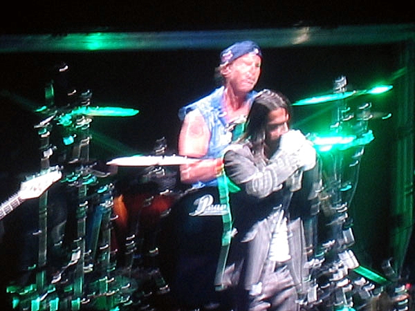 a man playing on a drums next to a girl on a stage