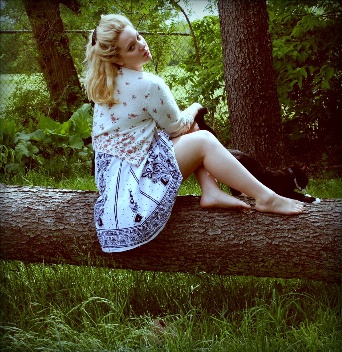 there is a woman sitting on the log holding a cat