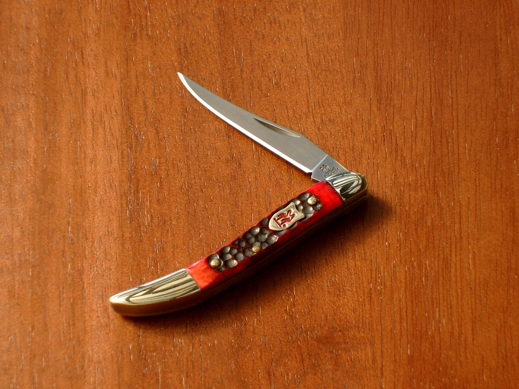 an orange and gold colored pocket knife with white trim