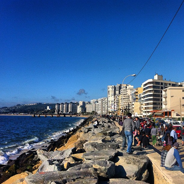 many people stand on the edge of a city near the ocean