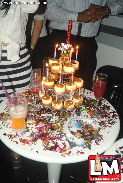 a couple standing around a cake with doughnuts and candles