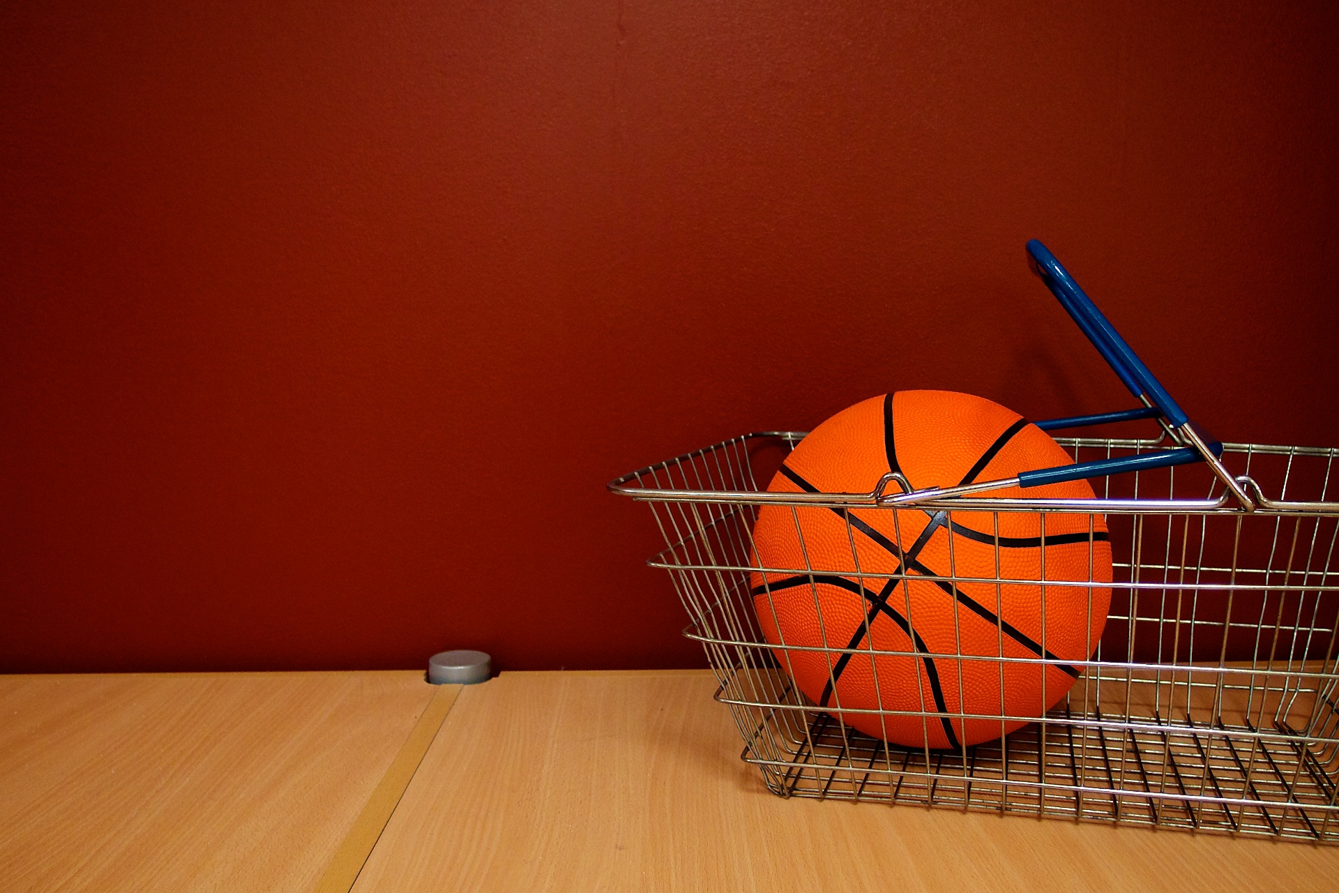 there is a wire basket and two oranges