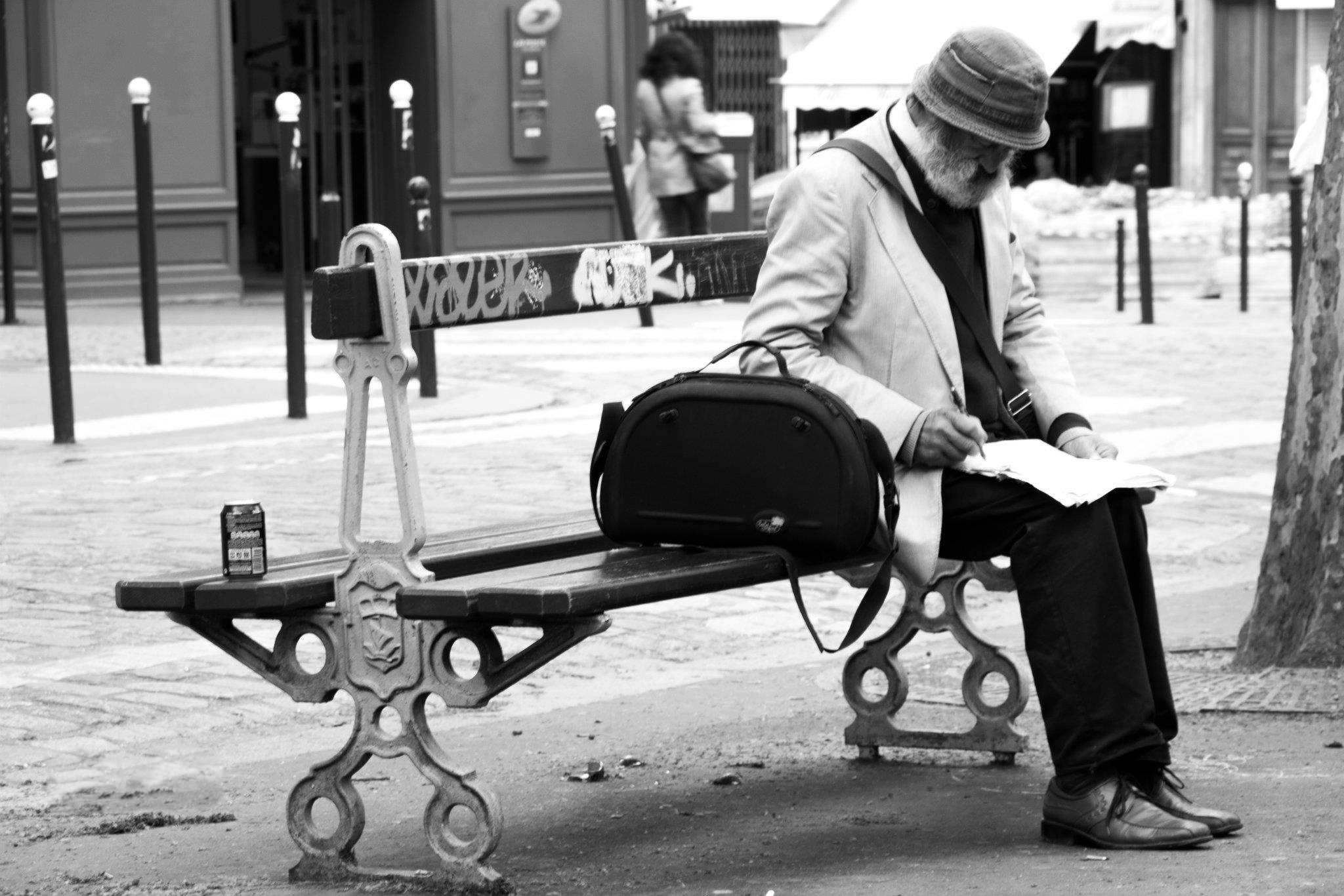 a man sitting on a bench reading a paper