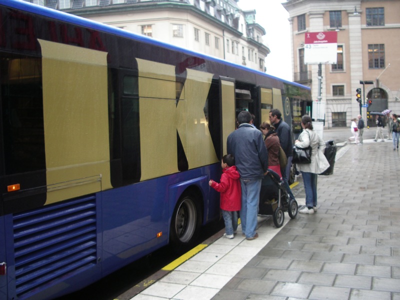 people boarding a public bus on the side walk