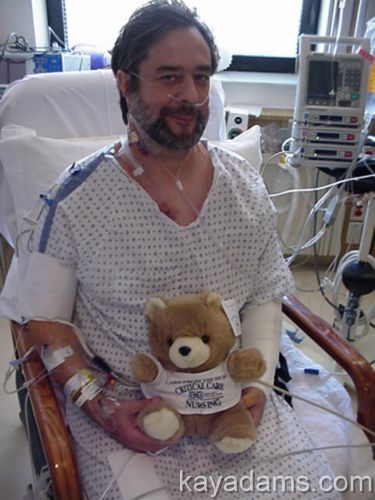a man is in a hospital bed holding a teddy bear