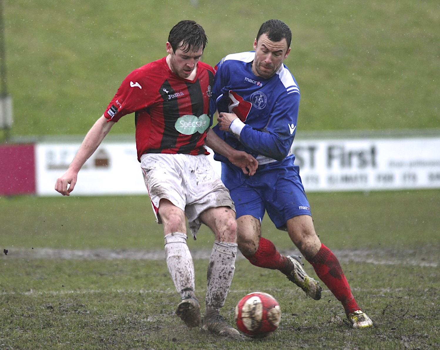 two men play soccer together on a grass field