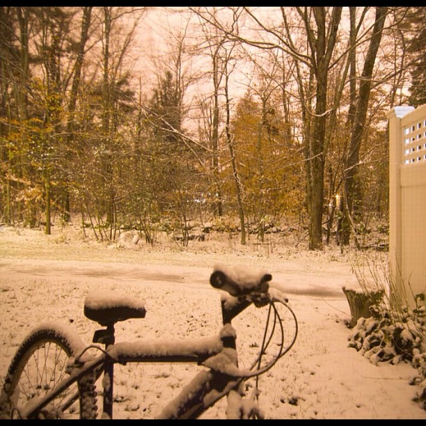 a bicycle covered in snow by a fence