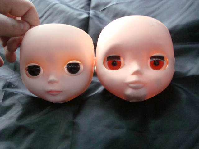two dolls with very small eyes, sitting on a sheet