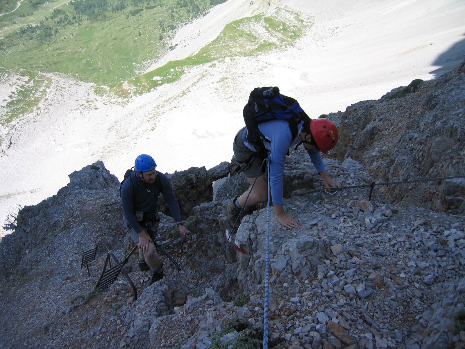 two men are climbing up a rocky hillside