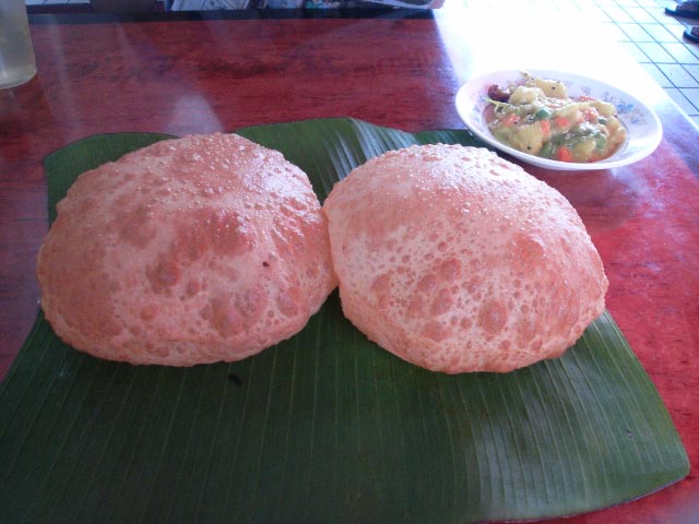 the two round, round, pink breads are on top of a large green leaf
