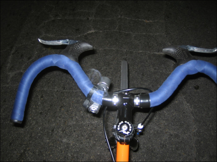 closeup of the handles of a bike with blue hoses