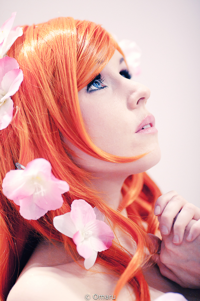 a beautiful red - haired woman with bright orange hair wearing pink flowers in her hair