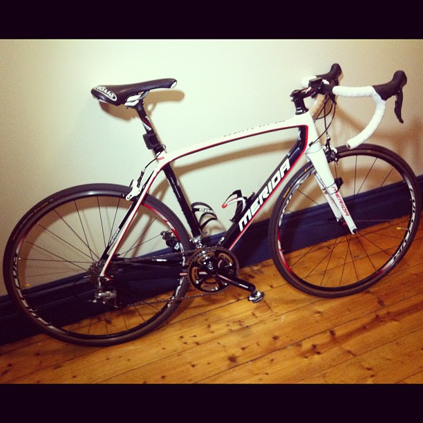 a white and black bike sitting on a wooden floor