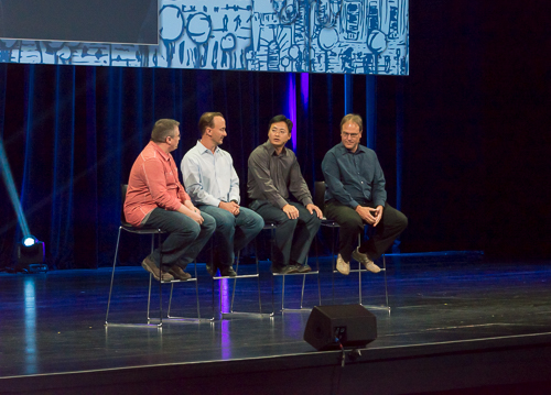 five men sitting on chairs talking on stage