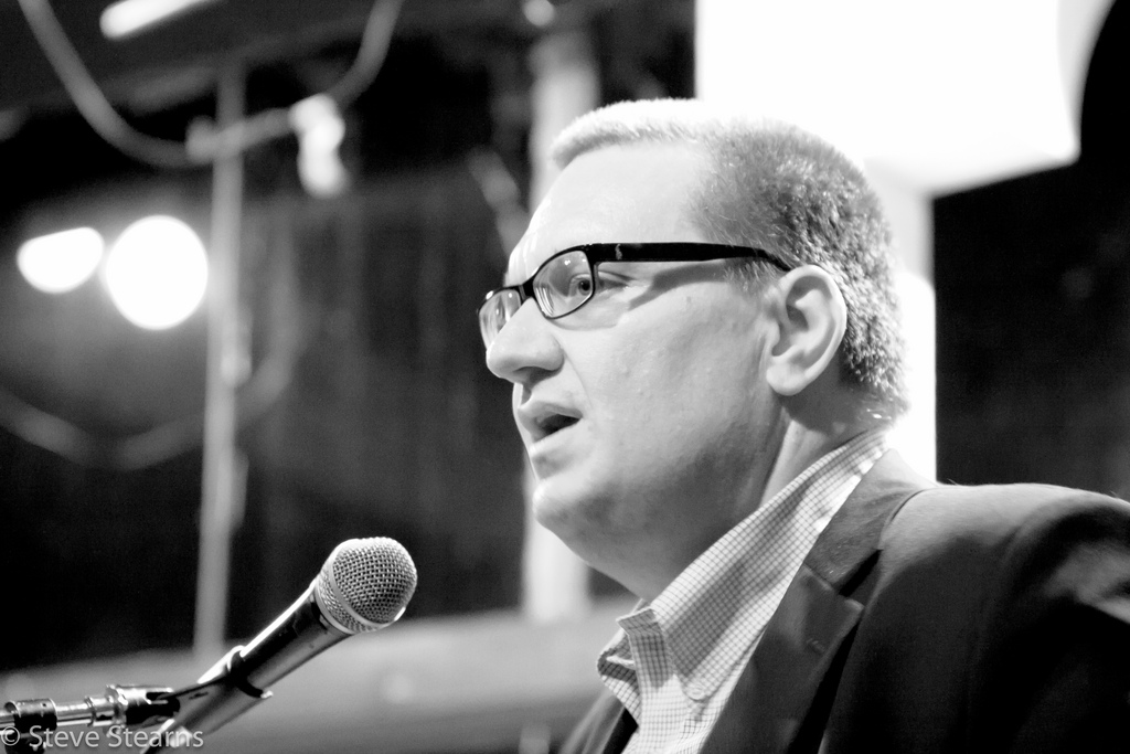 black and white image of man speaking into microphone