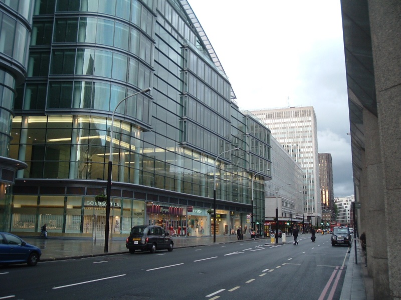 a busy street with glass buildings and pedestrians walking on the sidewalk