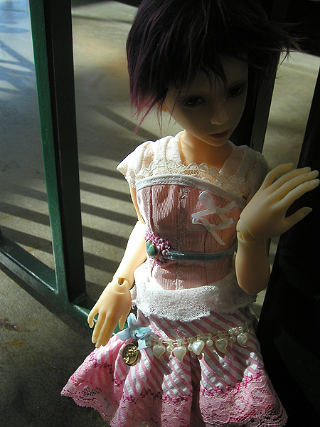 a toy doll is wearing a dress and holding a fake hand