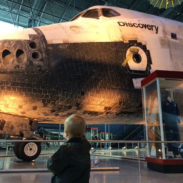 there is a child looking at a model of a space shuttle