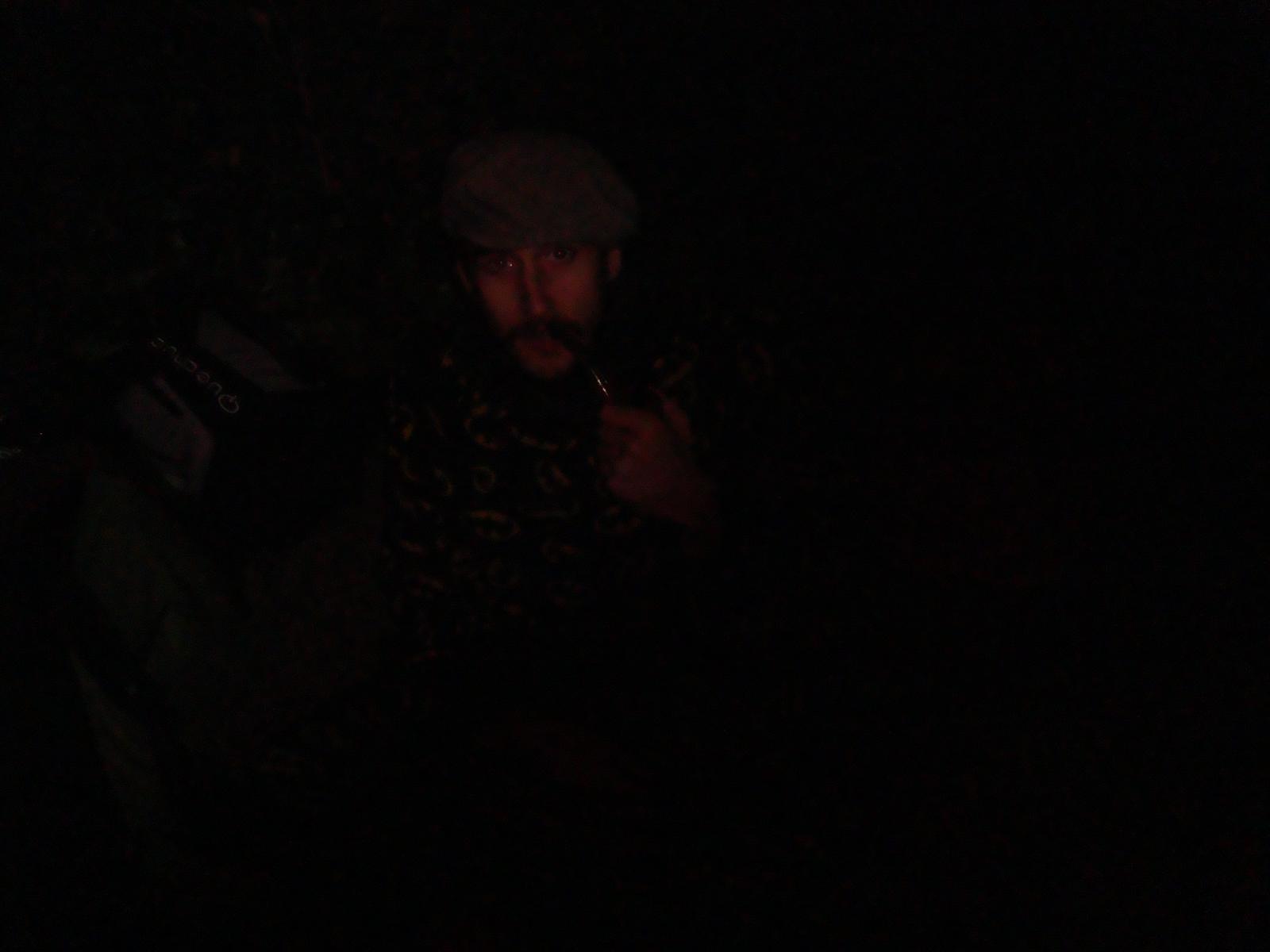 a man with a beard looking down in the dark