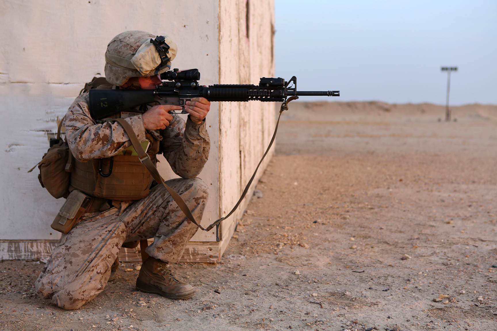 a soldier with a rifle sitting in the dirt