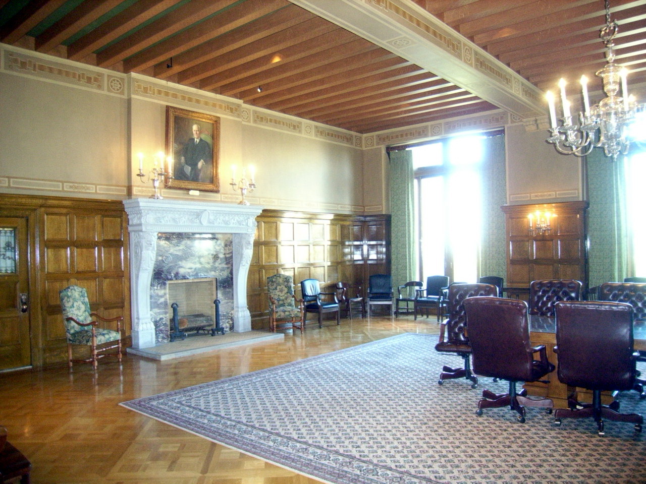 a room with a wooden paneled ceiling, two chairs and fireplace