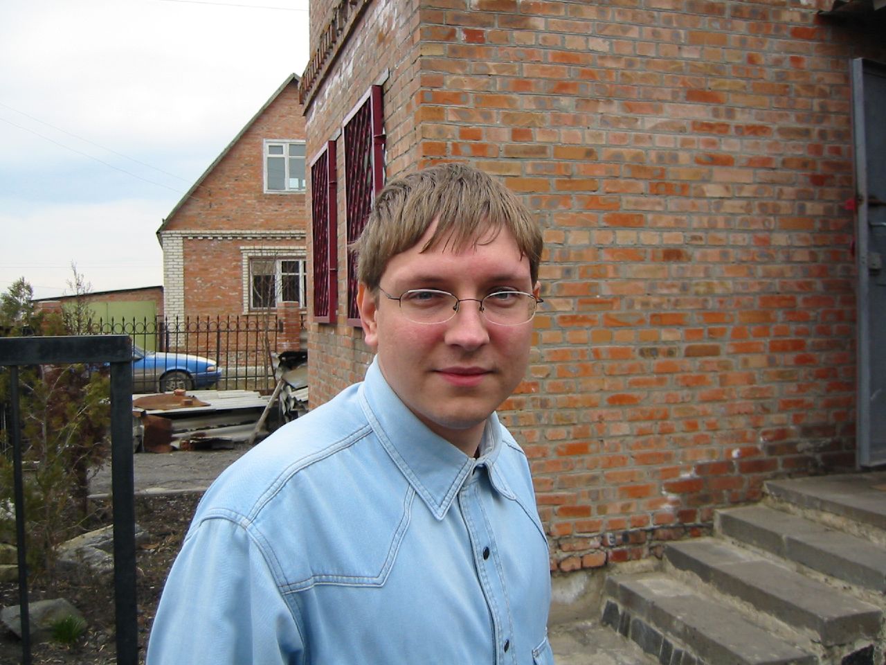 a man in glasses standing next to a building