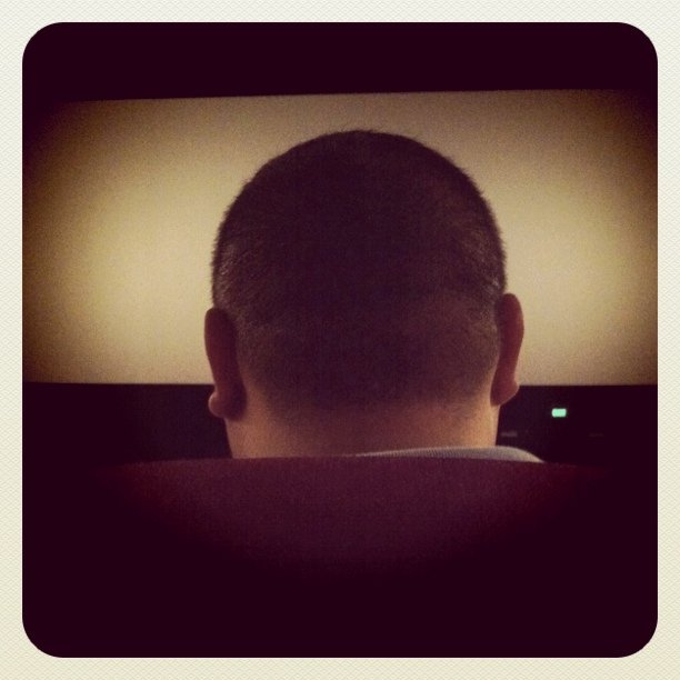 a man's back view of head with video in background