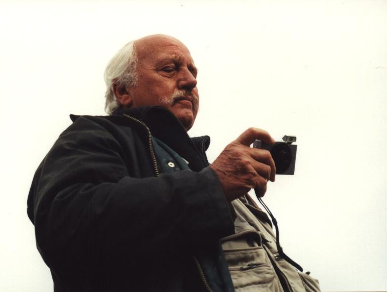 an older man holding a camera in his left hand