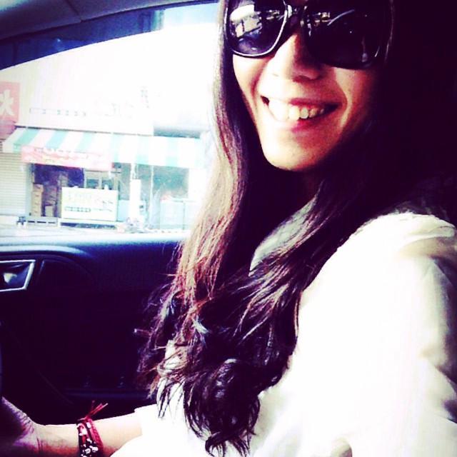 a smiling woman in sunglasses sitting inside of a car