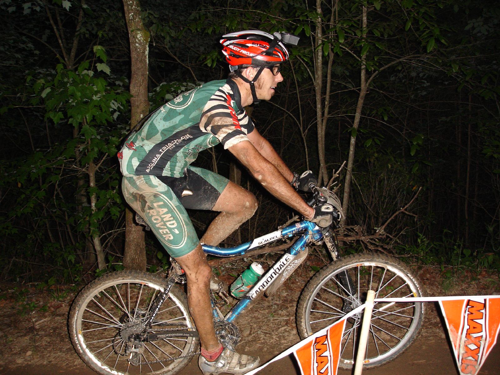 a man riding on a bicycle at night in the woods