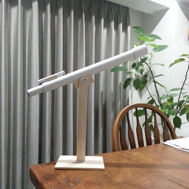 a table and chair with a plant in front of the blinds