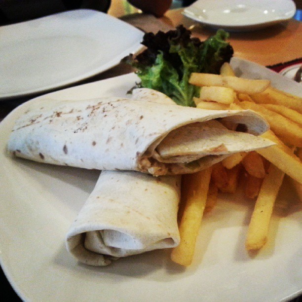 a burrito is on a plate with french fries