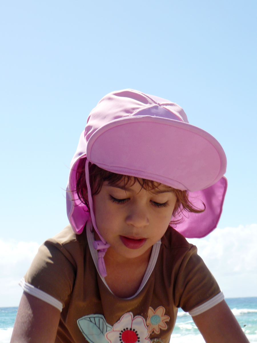 a girl in a brown shirt with a pink hat on