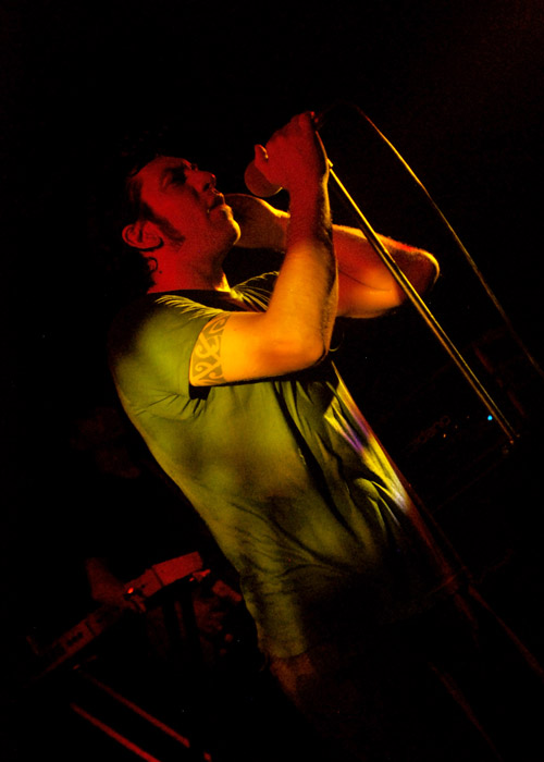 a man holding a microphone up to his ear at night