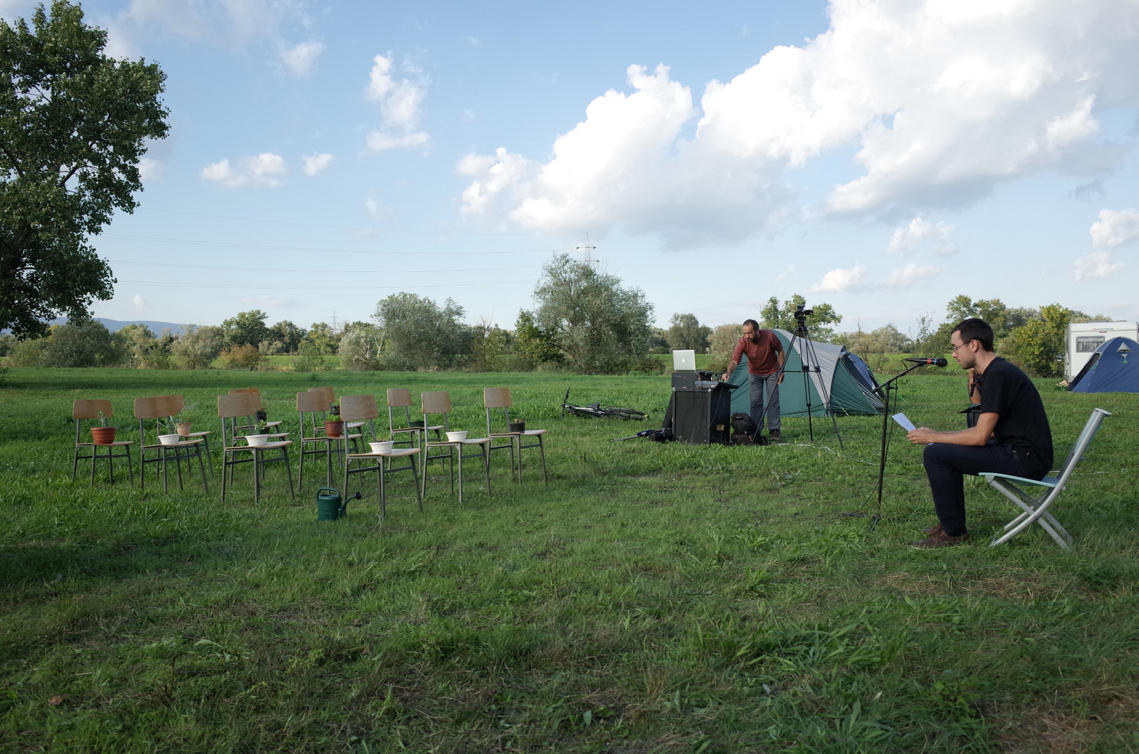 a man sits in a chair outside in a field near chairs