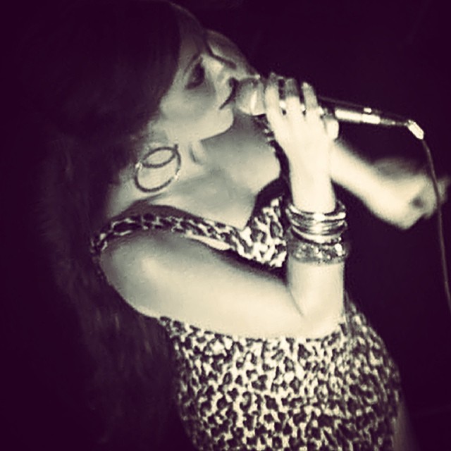 a woman in a short leopard dress singing into a microphone