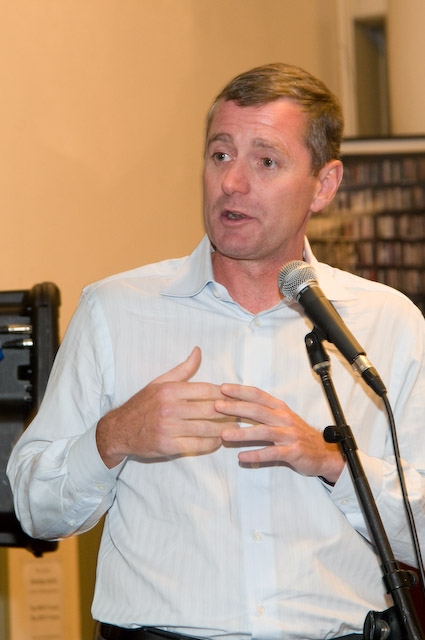 a man standing next to a microphone giving a speech