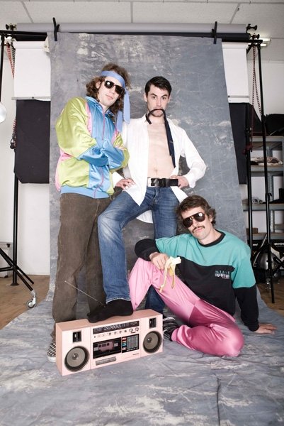 three men standing in front of an boom box