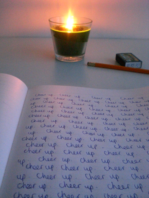 an open book on a table with writing and a candle in the background