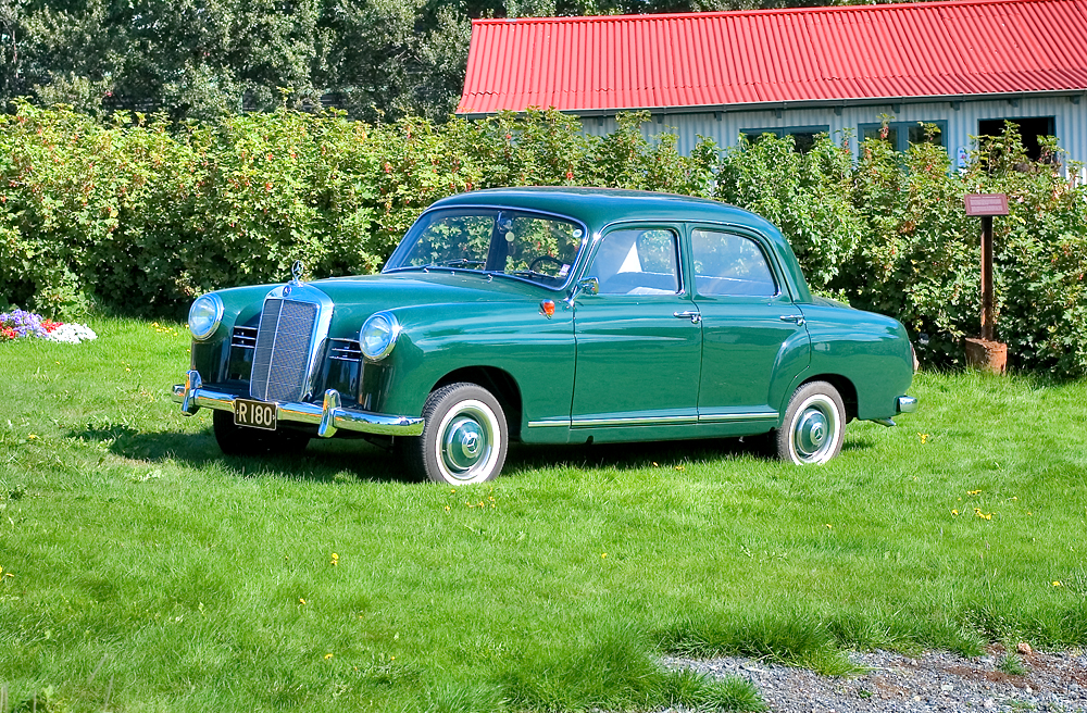 an old car is sitting in a field near some flowers