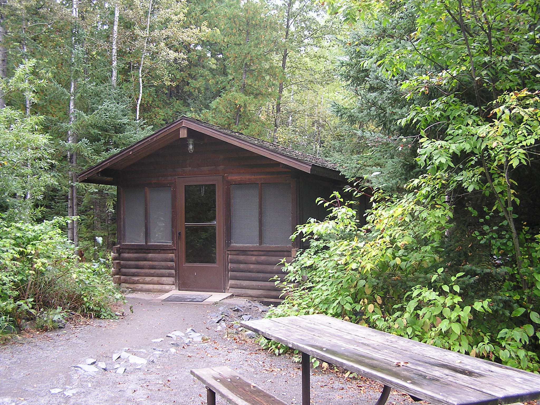 there is a small cabin with picnic table in the woods
