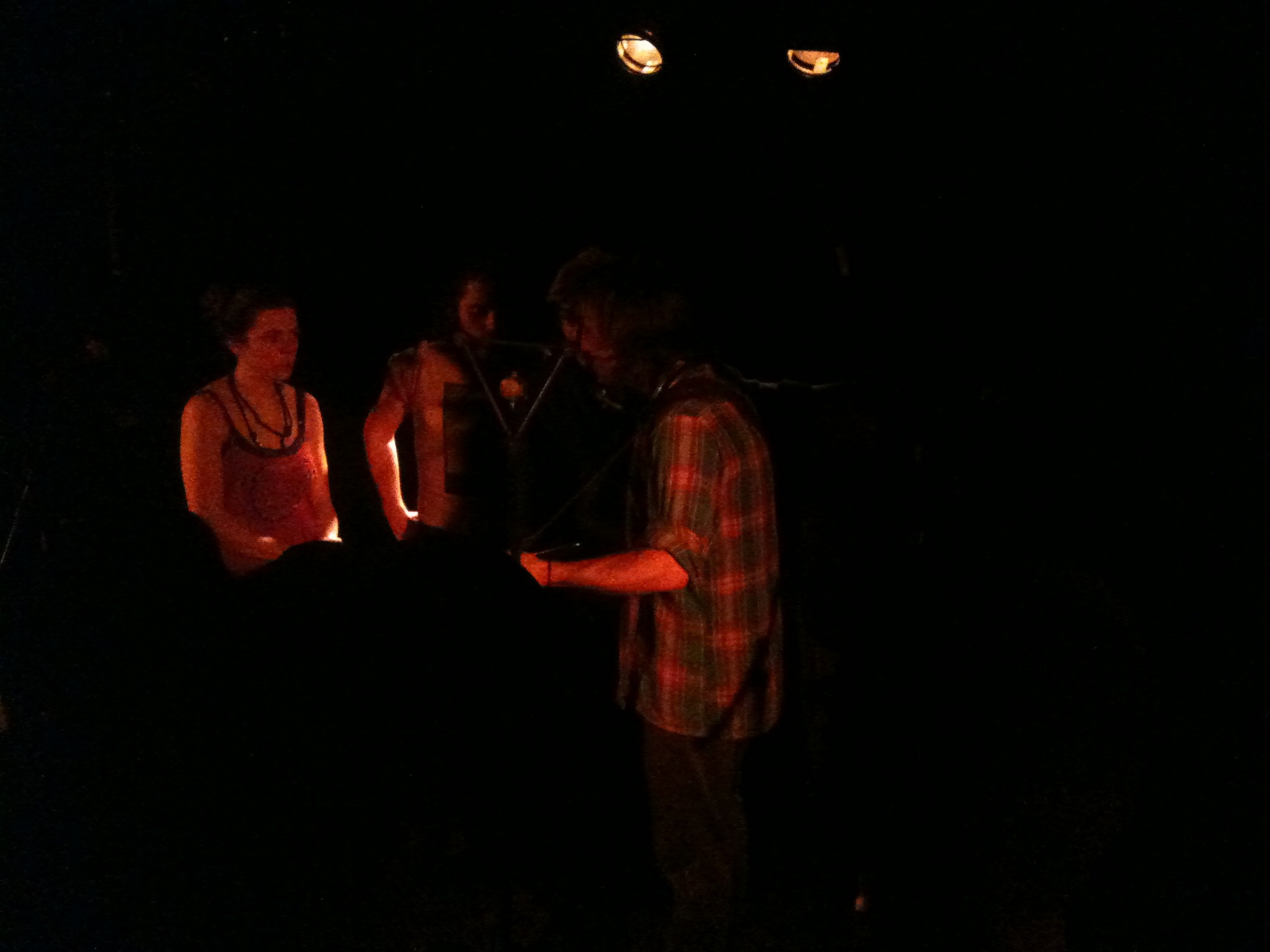 three men standing around the same person who is holding a lit candle