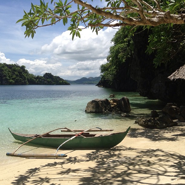 a green boat on the sand near the water