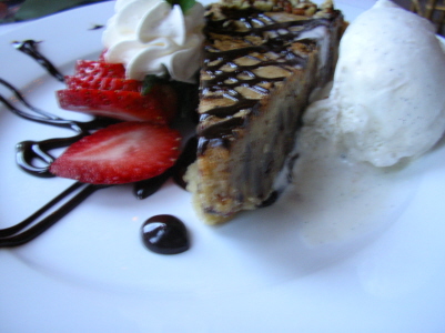 a piece of chocolate cake with white cream, strawberries and ice cream