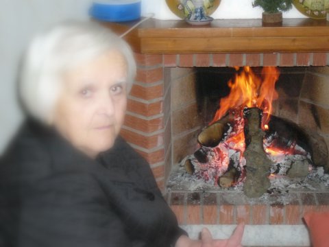 a woman is holding up a plate by a fireplace