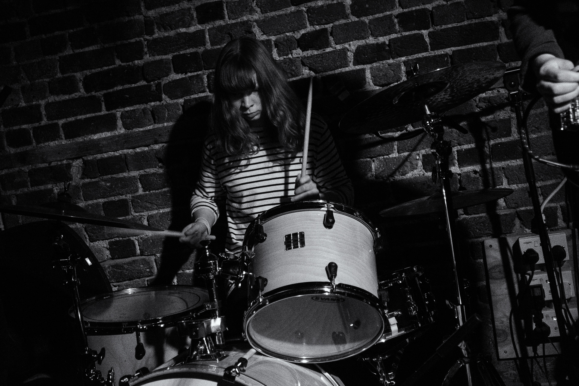 a woman playing drums in front of a brick wall