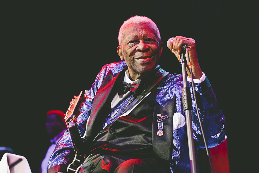 an old man sitting and smiling with his microphone